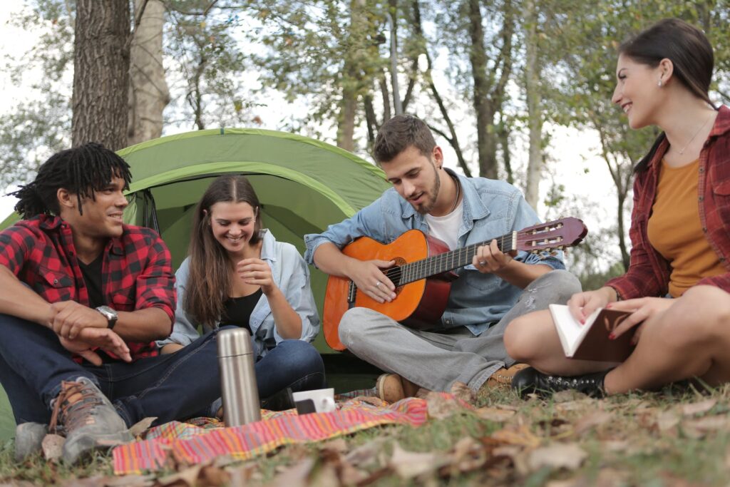 Acoustic Guitar Played By a Man Sitting On Grass Field